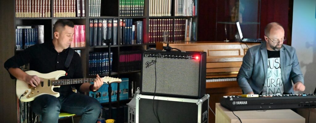Od lewej: Maciej Żołnierzów grający na gitarze i Grzegorz Jurkiewicz siedzący przy klawiszach.