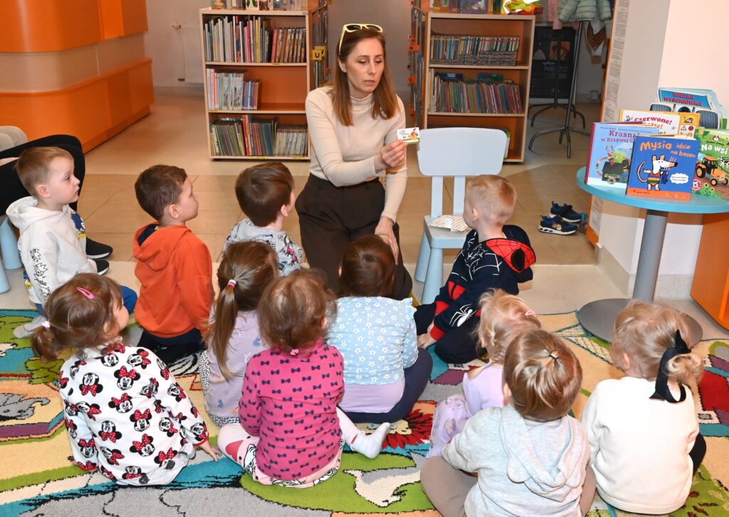 Bibliotekarka Izabela Szczyż pokazuje przedszkolakom kartonową książkę.