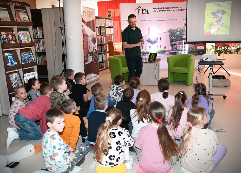 Mężczyzna przed siedzacymi dziećmi.