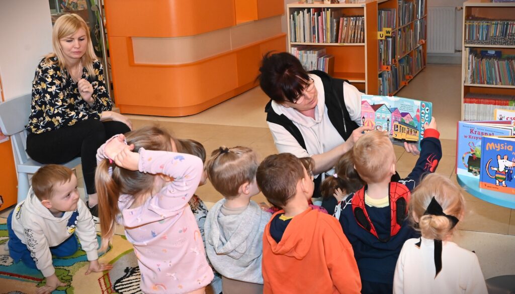 Bibliotekarka Irena Kozłowska pokazuje przedszkolakom książkę dźwiękową.