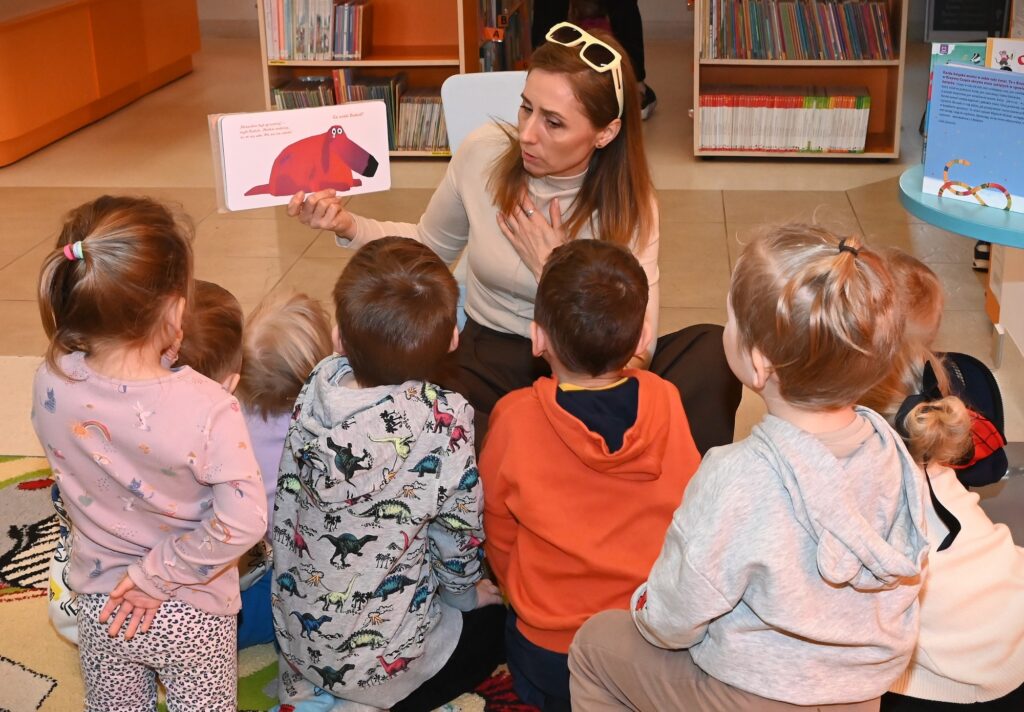 Bibliotekarka Izabela Szczyż pokazuje przedszkolakom kartonową książkę.