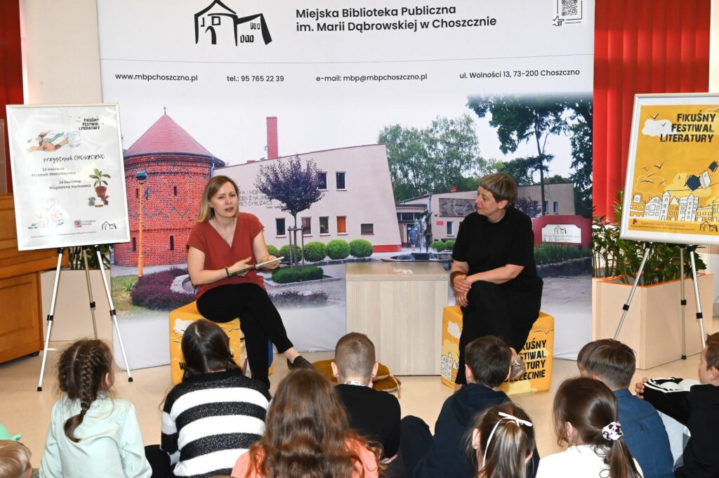 Przed dziećmi siedzą na pufach od lewej: Magdalena Kiełbowicz. i Małgorzata Narożna.