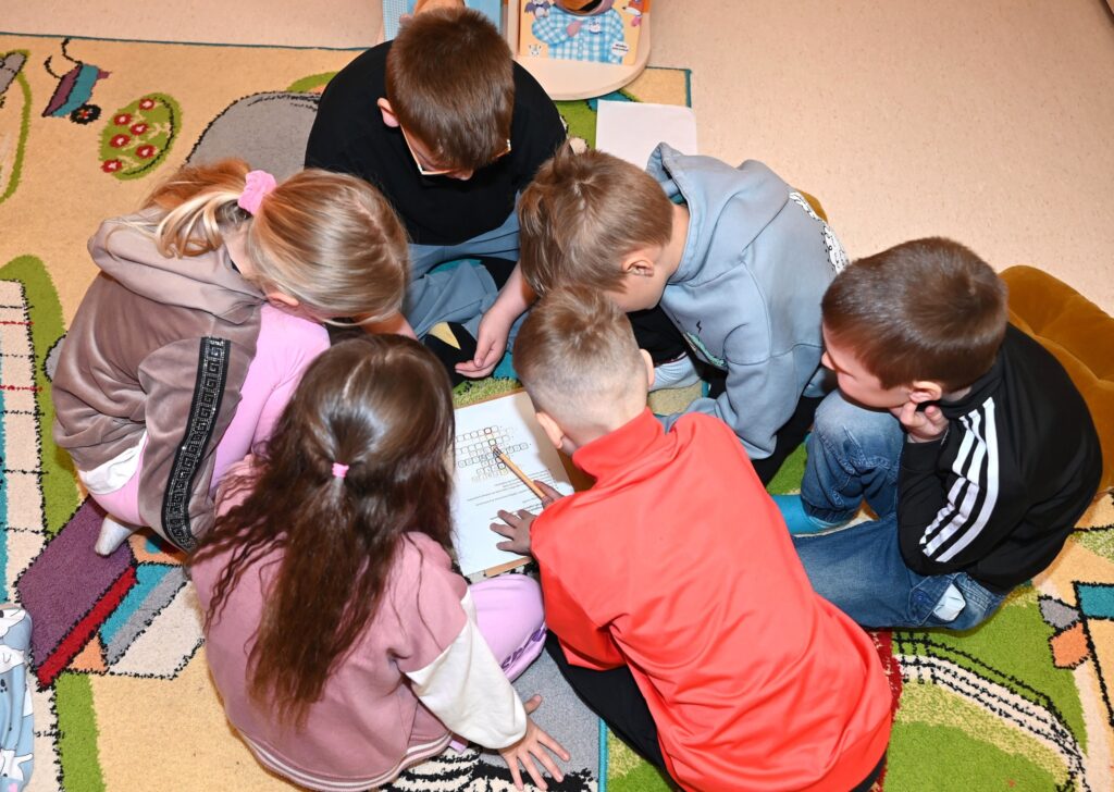 Dzieci pracują w grupie, rozwiązując krzyżówkę.