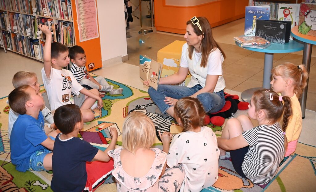Bibliotekarka Izabela Szczyż pokazuje dzieciom książkę zn rybką.