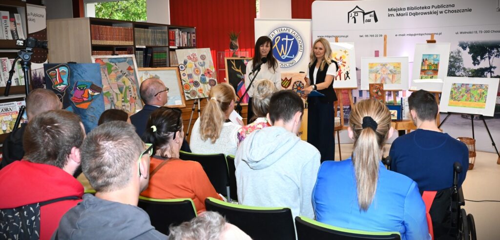 Katarzyna Jezierska i Elwira Najdora stoją przed publicznością. Za nimi obrazy.