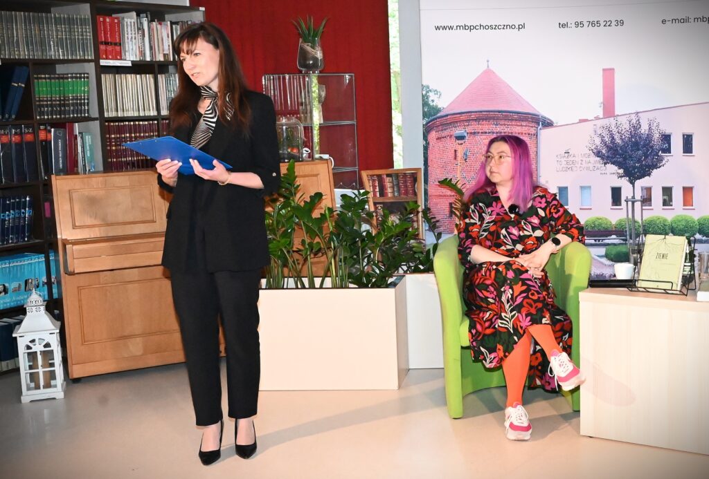 Z lewej strony stoi dyrektor biblioteki Katarzyna Jezierska, z prawej strony nieco z tyłu siedzi Karolina Ćwiek-Rogalska.