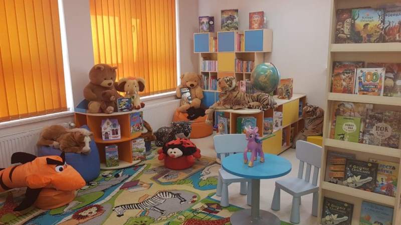 Kącik Malucha - na meblach stoją książki, zabawki. Na dywanie leżą siedziska i pluszowe duże zabawki.