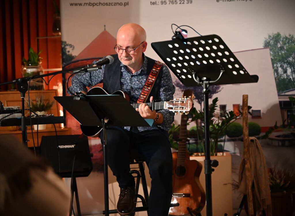 Marek Staniewski grający na gitarze. Przed nim pulpit na nuty.