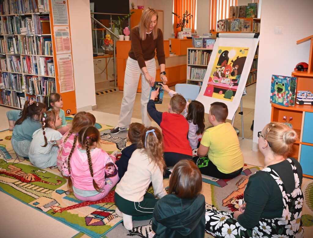 Bibliotekarka Izabela Szczyż pokazuje dzieciom książkę o Edziu.