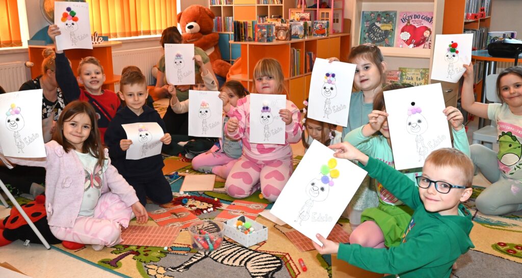 Dzieci pokazują swoje prace plastyczne.