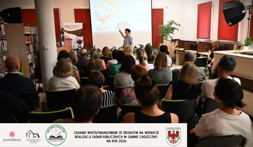 Justyna Żejmo wskazuje coś na ekranie. Z przodu siedzi publiczność.