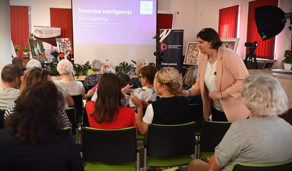 Dorota Dżega-Pietruszkiewicz podaje osobom z publiczności karteczki do wylosowania. 