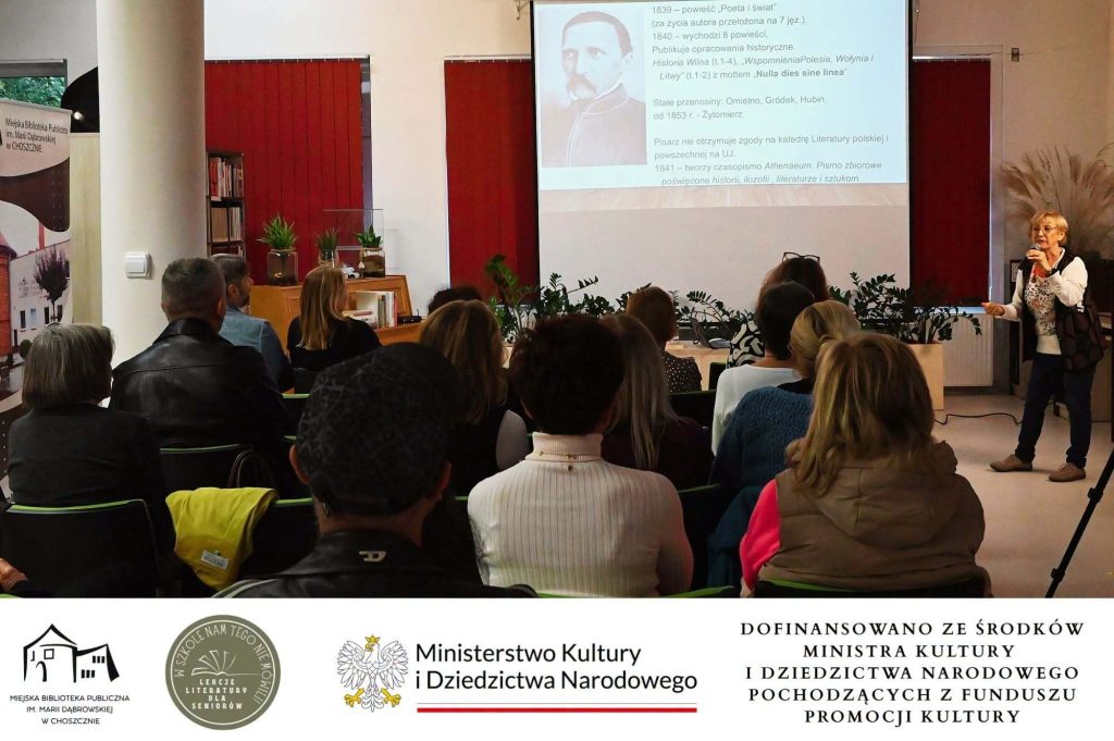 Cecylia Judek przed publicznością. Za nią na ekranie slajd o Kraszewskim.