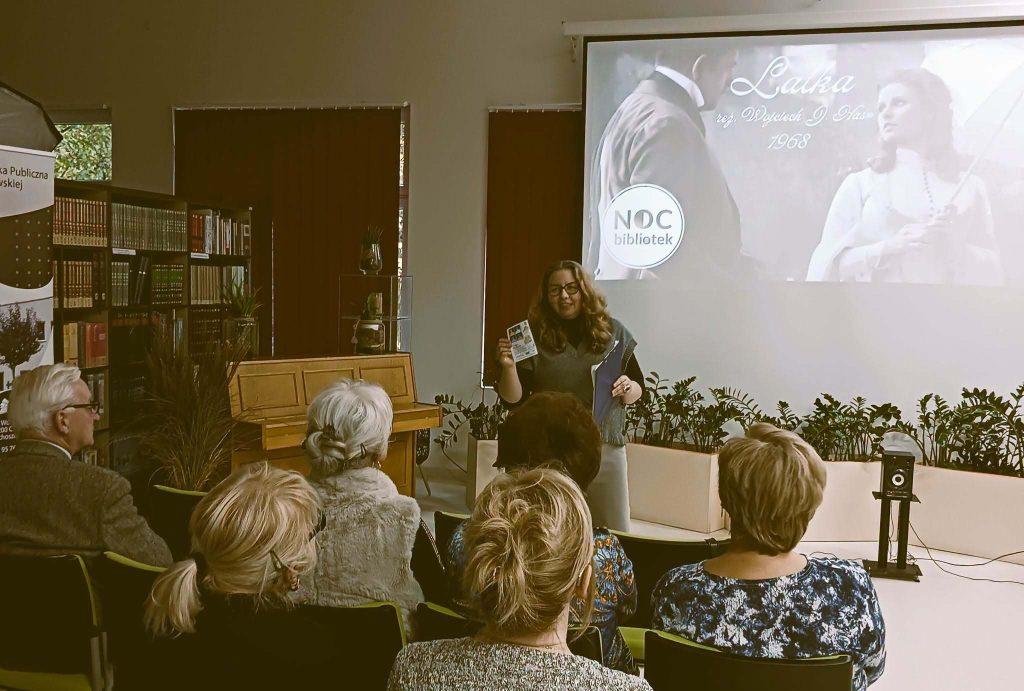 Anna Stekiewicz przed publicznością. Na ekranie fotos z filmu i tytuł spotkania.